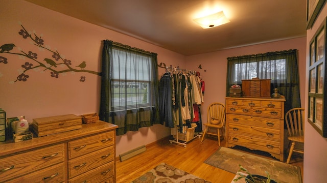 bedroom featuring a baseboard heating unit and light wood-style floors