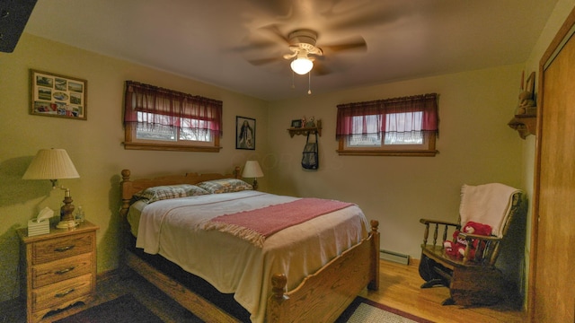 bedroom featuring a ceiling fan, wood finished floors, and a baseboard radiator