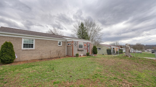 rear view of property with a lawn, an outdoor structure, and fence