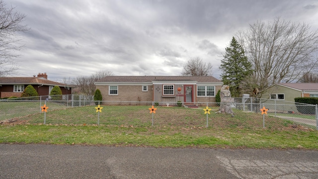 view of front of property featuring a fenced front yard, brick siding, and a front lawn
