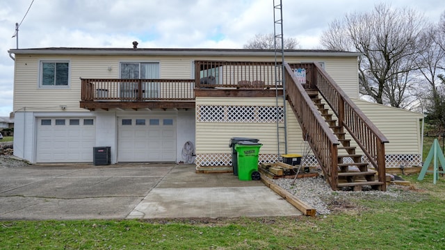 rear view of property with central AC unit, concrete driveway, stairs, and a garage