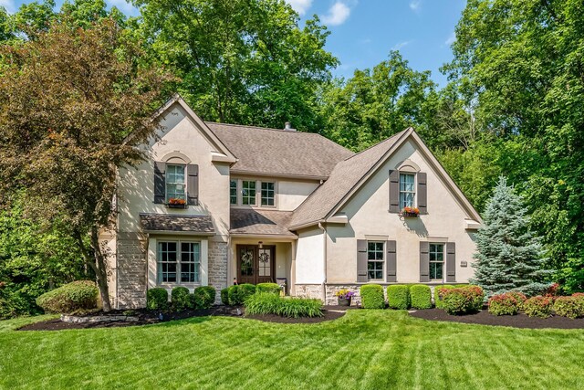 9047 Sequoia Ct, Plain City, OH 43064 - view of front of property with stucco siding, stone siding, a front lawn, and roof with shingles