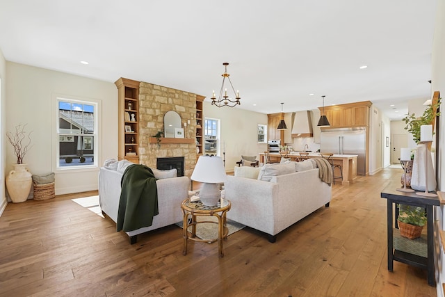 living room with a stone fireplace, recessed lighting, a healthy amount of sunlight, and light wood-type flooring
