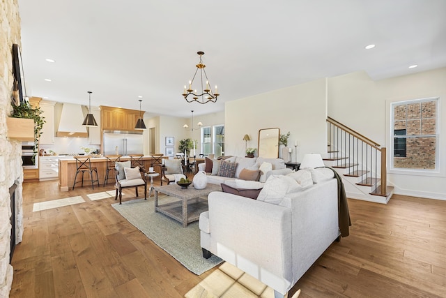 living room featuring a chandelier, recessed lighting, stairs, and light wood-style floors