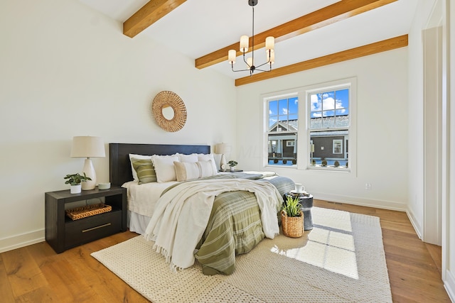 bedroom with beamed ceiling, baseboards, an inviting chandelier, and wood finished floors