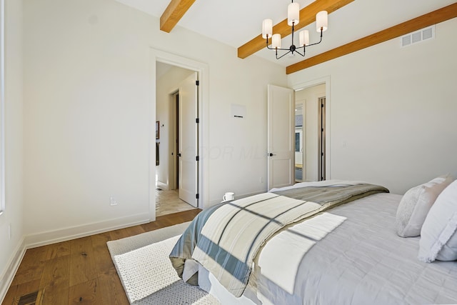 bedroom featuring beam ceiling, visible vents, an inviting chandelier, and wood finished floors