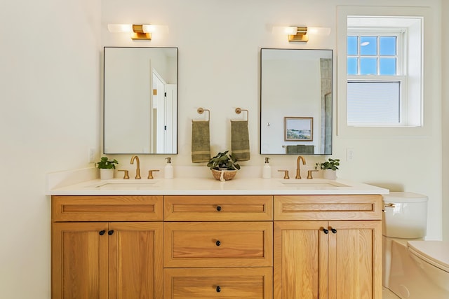 full bath with double vanity, toilet, and a sink