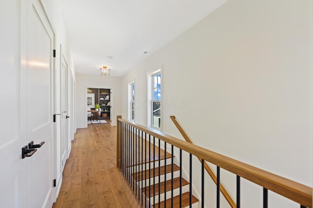 hallway featuring an inviting chandelier, an upstairs landing, and light wood finished floors