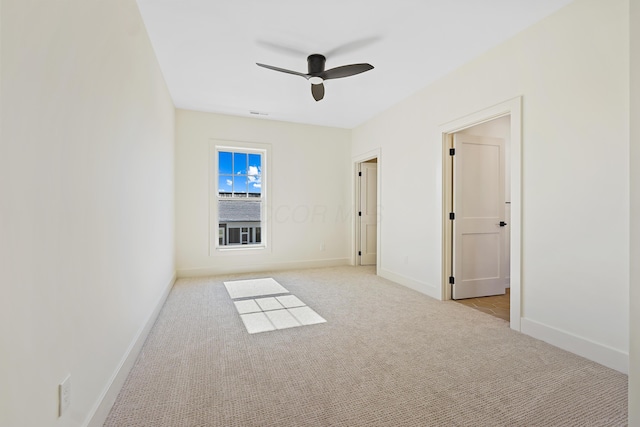 carpeted spare room with baseboards and a ceiling fan