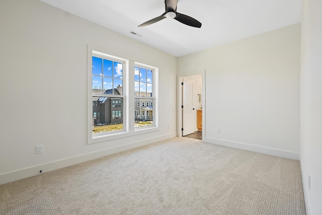 carpeted spare room with visible vents, baseboards, and a ceiling fan