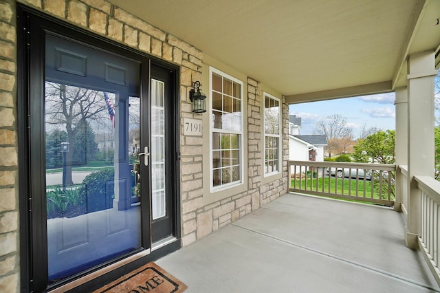 property entrance with covered porch and stone siding