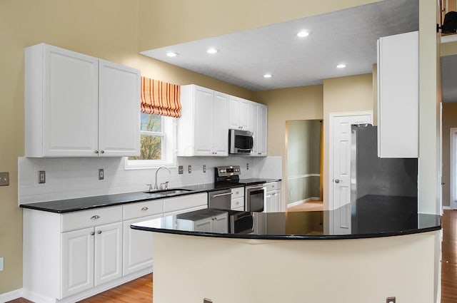 kitchen with stainless steel appliances, a sink, tasteful backsplash, white cabinetry, and recessed lighting