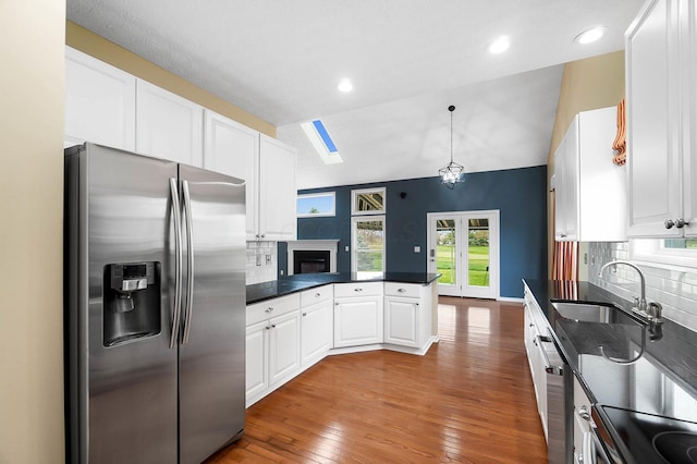 kitchen featuring stainless steel appliances, a peninsula, dark countertops, white cabinetry, and french doors