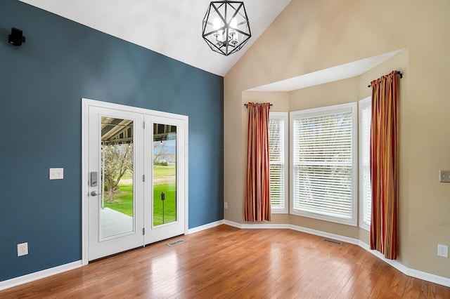 doorway featuring high vaulted ceiling, healthy amount of natural light, a chandelier, wood finished floors, and baseboards