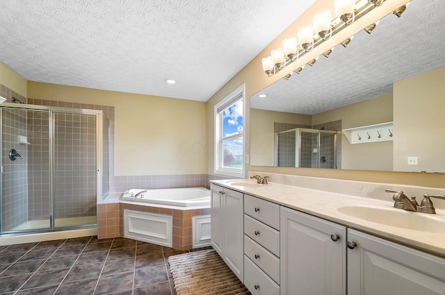 full bathroom featuring a textured ceiling, a stall shower, a bath, double vanity, and tile patterned flooring