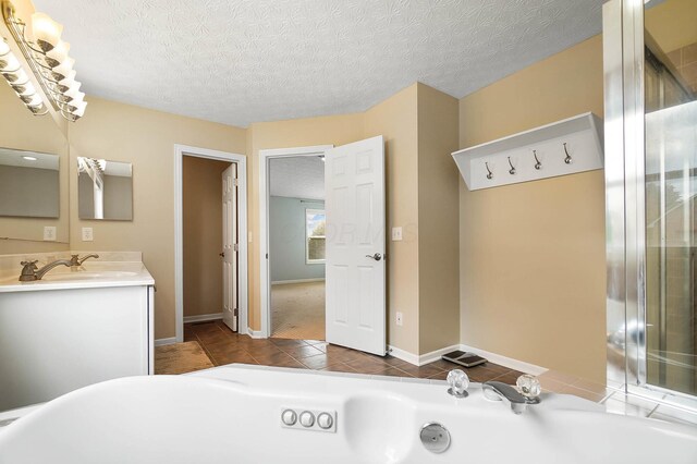 bathroom with a whirlpool tub, a textured ceiling, tile patterned floors, vanity, and baseboards