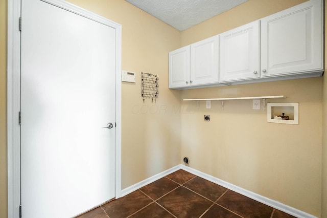 clothes washing area with washer hookup, cabinet space, hookup for an electric dryer, dark tile patterned floors, and baseboards