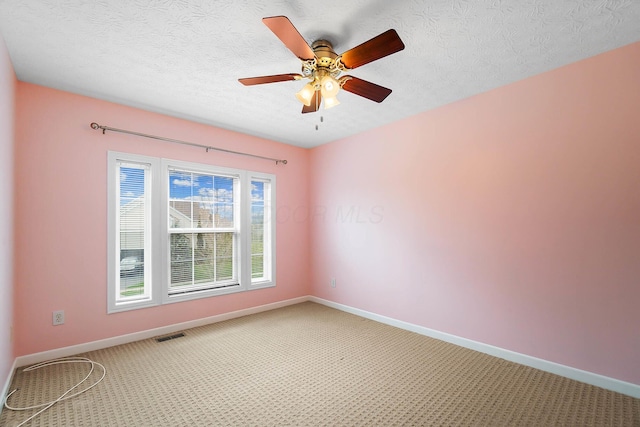 carpeted spare room with baseboards, ceiling fan, and a textured ceiling