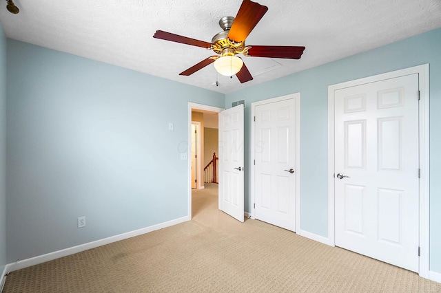 unfurnished bedroom featuring light colored carpet, baseboards, and ceiling fan