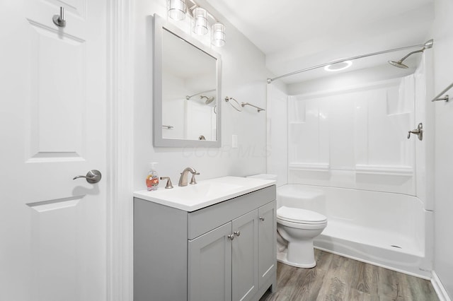 full bathroom with a shower, wood finished floors, toilet, and vanity