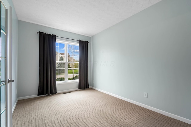 carpeted spare room with baseboards and a textured ceiling
