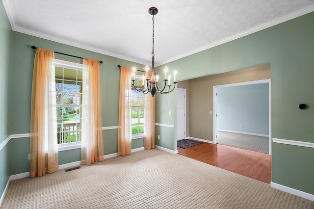 unfurnished room with a chandelier, carpet, baseboards, and crown molding