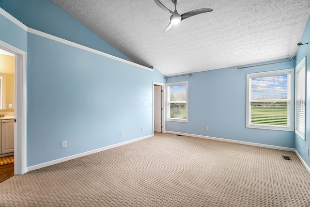 unfurnished room featuring a ceiling fan, light colored carpet, lofted ceiling, a textured ceiling, and baseboards