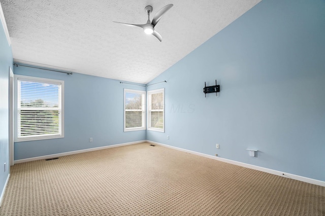 unfurnished room with a textured ceiling, light carpet, baseboards, a ceiling fan, and vaulted ceiling