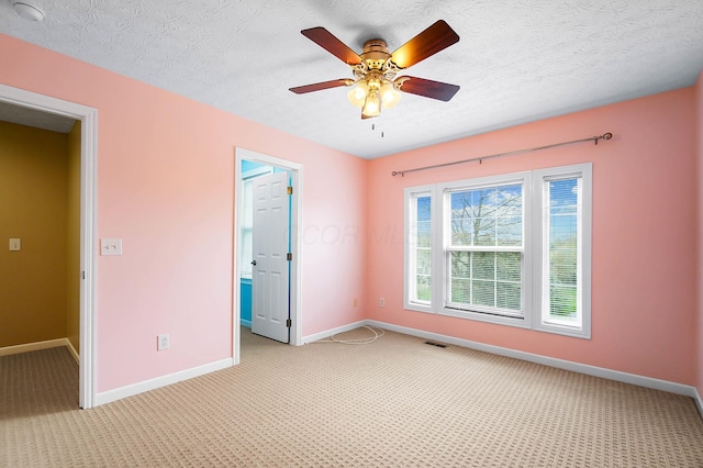 unfurnished room with baseboards, light carpet, a smoke detector, a ceiling fan, and a textured ceiling