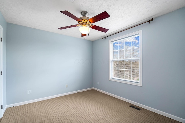 spare room featuring carpet floors, a ceiling fan, baseboards, and a textured ceiling