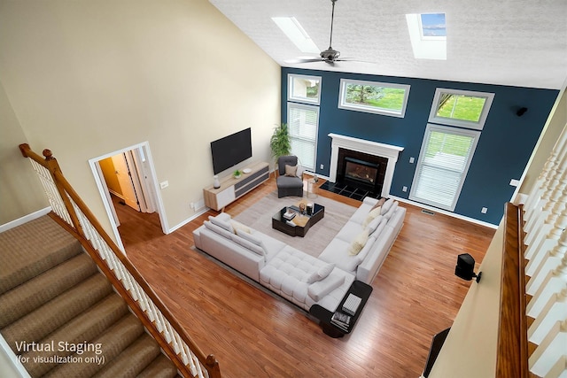 living area featuring a skylight, stairway, a textured ceiling, a tile fireplace, and wood finished floors
