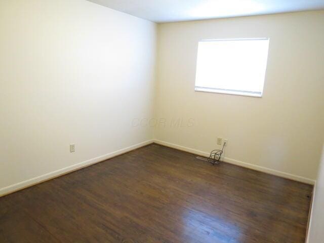 spare room featuring baseboards and wood finished floors