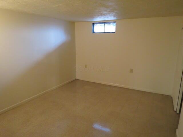 basement with a textured ceiling and baseboards