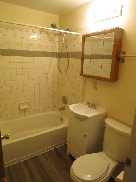 bathroom with toilet, vanity, bathtub / shower combination, and wood finished floors