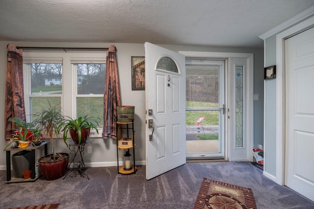 foyer featuring baseboards, carpet floors, and a textured ceiling