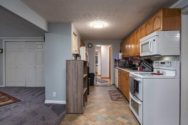 kitchen with a textured ceiling, white appliances, brown cabinetry, light countertops, and baseboards