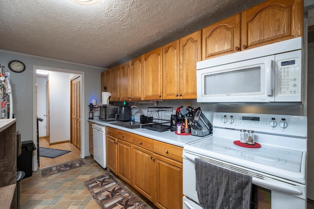 kitchen featuring brown cabinets, a sink, a textured ceiling, white appliances, and light countertops