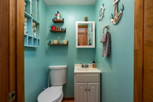 bathroom with a textured ceiling, toilet, and vanity