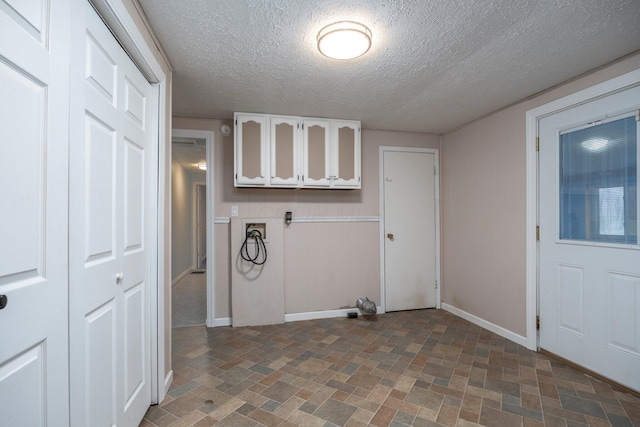 washroom with washer hookup, cabinet space, baseboards, and a textured ceiling