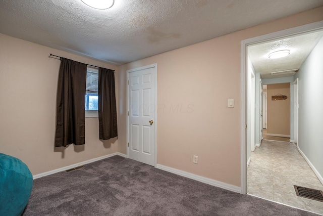 unfurnished bedroom featuring visible vents, a textured ceiling, and carpet flooring