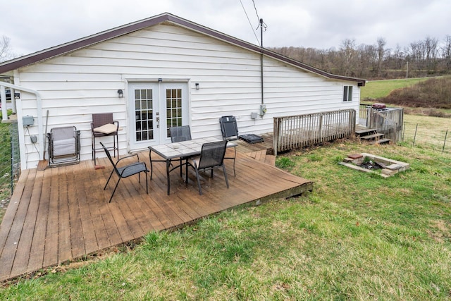 back of house with a deck, outdoor dining area, french doors, and a lawn