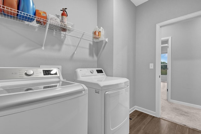 clothes washing area with dark wood finished floors, independent washer and dryer, laundry area, and baseboards