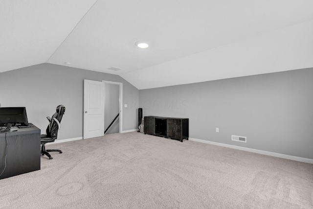 carpeted office space featuring baseboards, vaulted ceiling, and visible vents