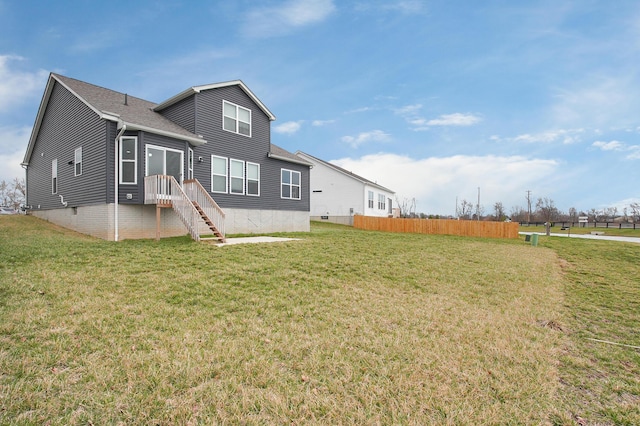 back of property with a shingled roof, fence, and a lawn