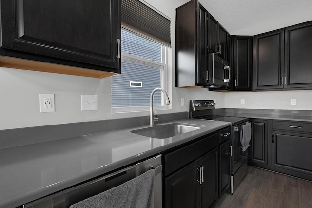 kitchen with dishwasher, stainless steel microwave, black / electric stove, a sink, and dark cabinetry