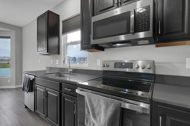 kitchen with a sink, stainless steel appliances, dark wood-style floors, and a wealth of natural light
