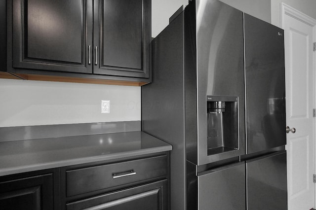 kitchen with dark cabinetry and stainless steel refrigerator with ice dispenser