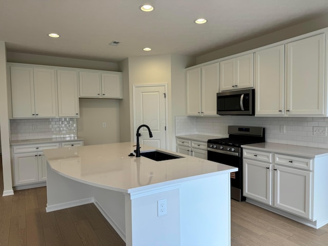 3780 Brody Dr Lot 187, Grove City, OH 43123 - kitchen with stainless steel appliances, light wood-style flooring, a center island with sink, tasteful backsplash, and white cabinetry