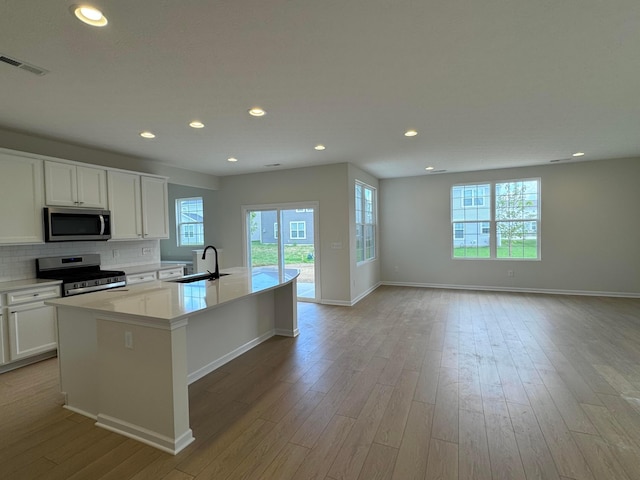 3780 Brody Dr Lot 187, Grove City, OH 43123 - kitchen featuring appliances with stainless steel finishes, a center island with sink, tasteful backsplash, white cabinetry, and light wood-type flooring