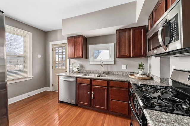1542 S 4th St, Columbus, OH 43207 - kitchen featuring light wood-style flooring, a sink, appliances with stainless steel finishes, baseboards, and stone counters